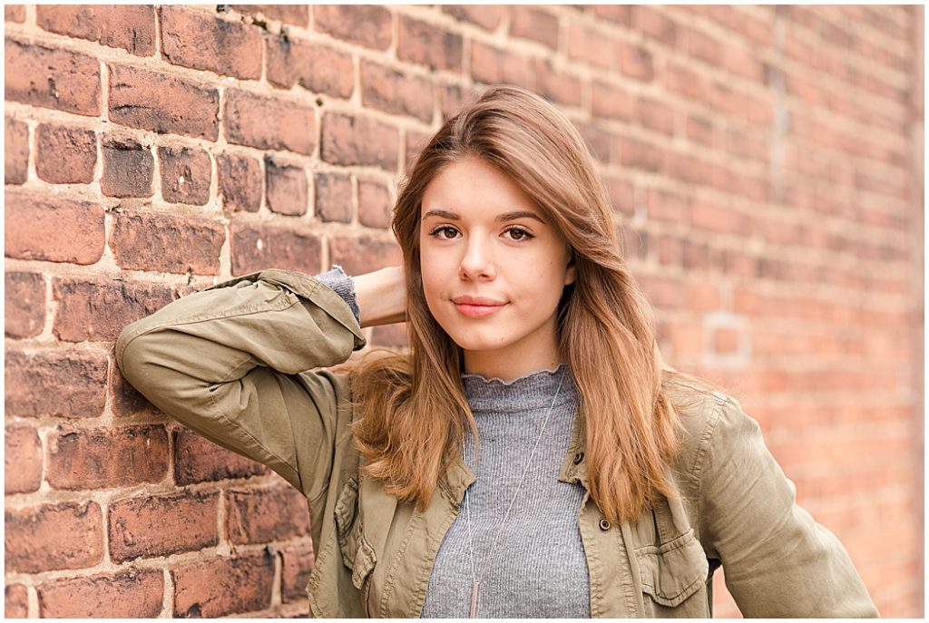 girl senior pictures in front of brick wall
